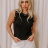 A sleek black top with pearl embellishments.