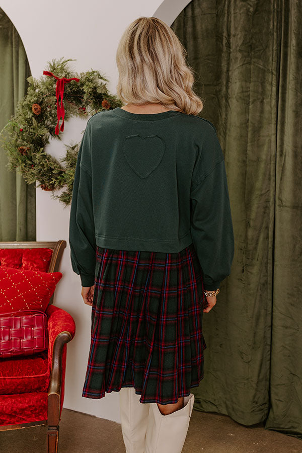 Winter-inspired plaid mini dress with a relaxed green top, styled with knee-high boots for a festive touch.