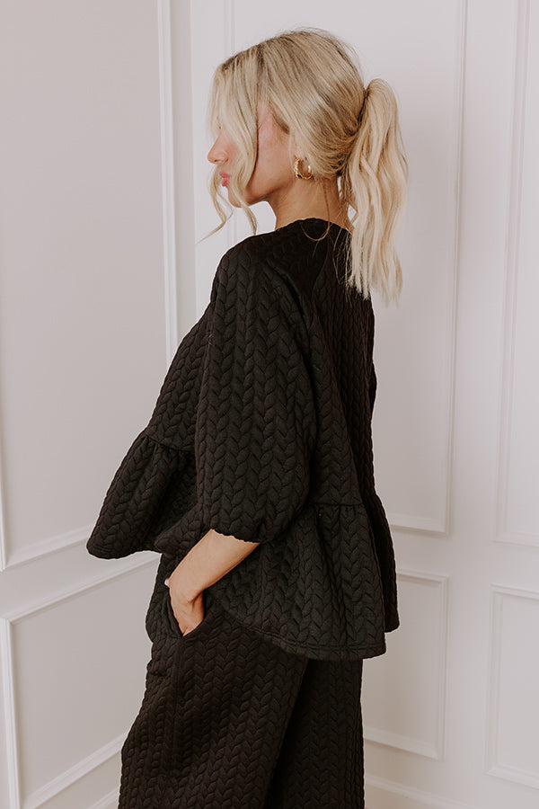 Black textured two-piece outfit with a peplum silhouette and wide-leg pants, ideal for casual winter styling.